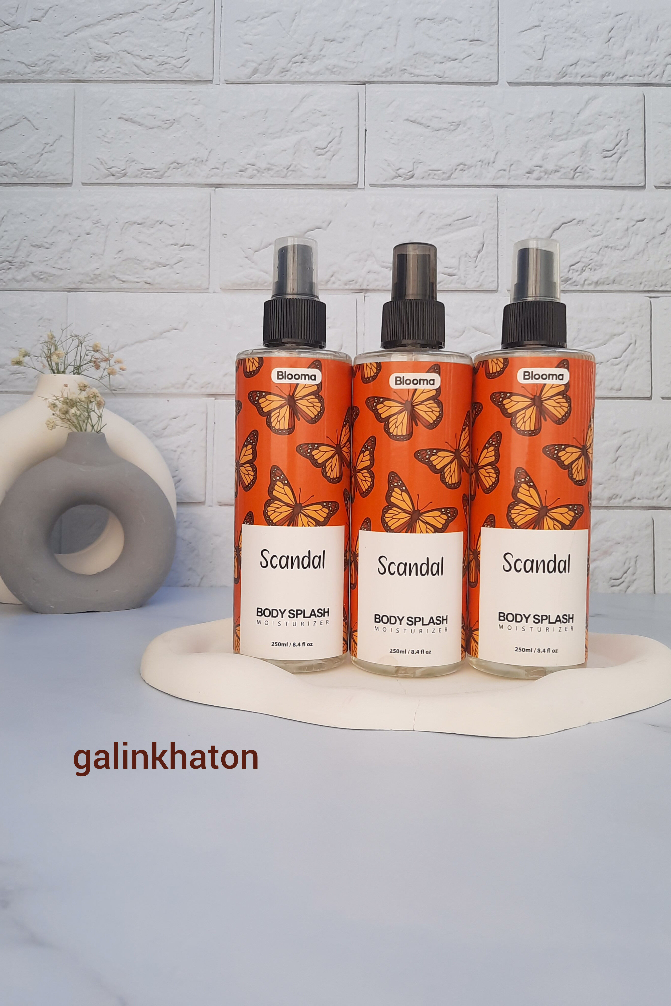 سه بادی اسپلش زنانه بلوما با رایحه اسکندل کنار هم روی پس ضمینه مینیمال سفید_اسپری بدن با ماندگاری طولانی ، عطر زنانه لوکس و دلنشین ، خرید آنلاین بادی اسپلش بلوما اصل با رایحه اسکندل از فروشگاه میکسین