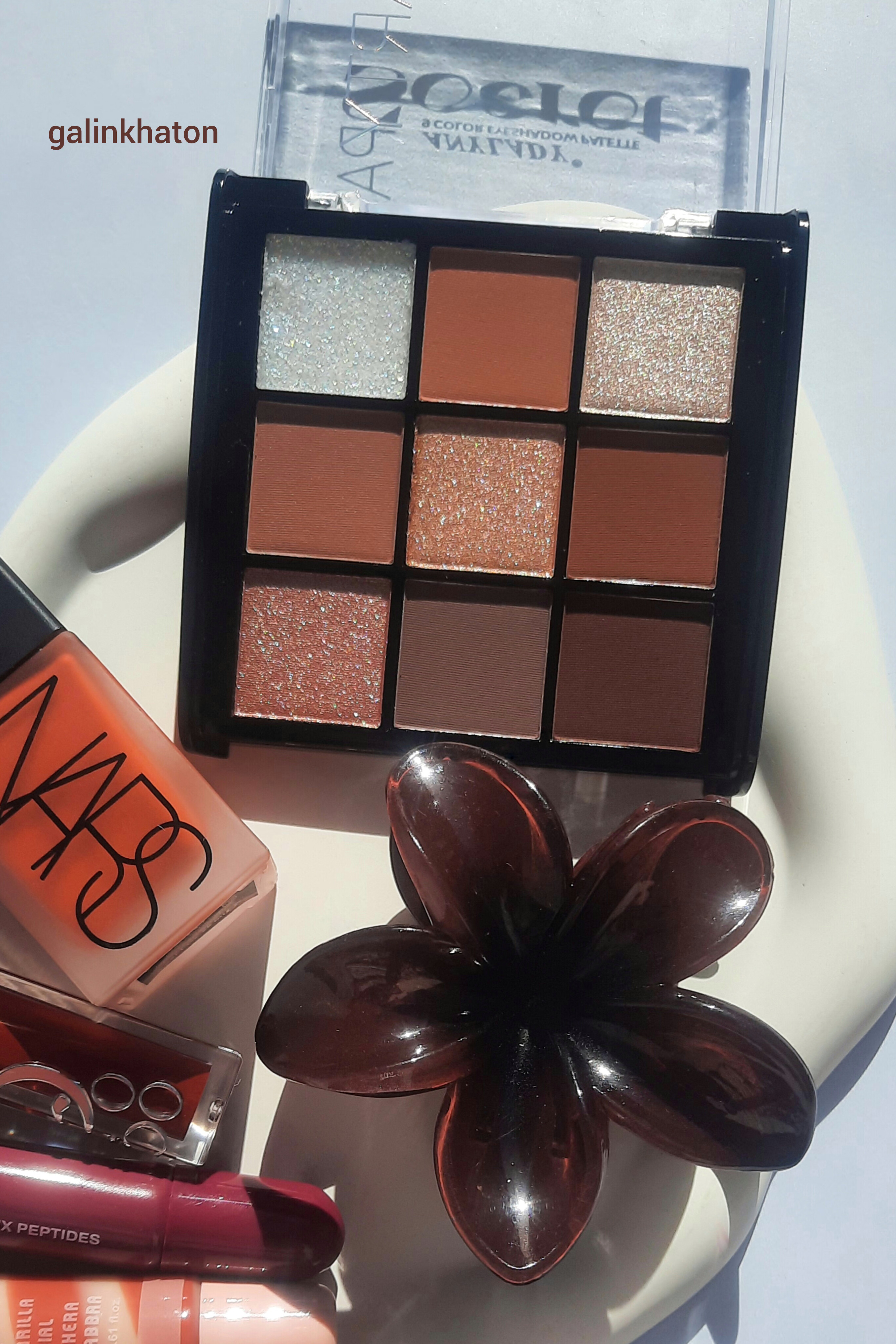 پالت سایه نود ۹ رنگ از برند آنیلیدی با تناژ قهوه‌ای براق در کنار رژگونه نارس و لیپ گلاس دیور روی زمینه سفید با نور طبیعی