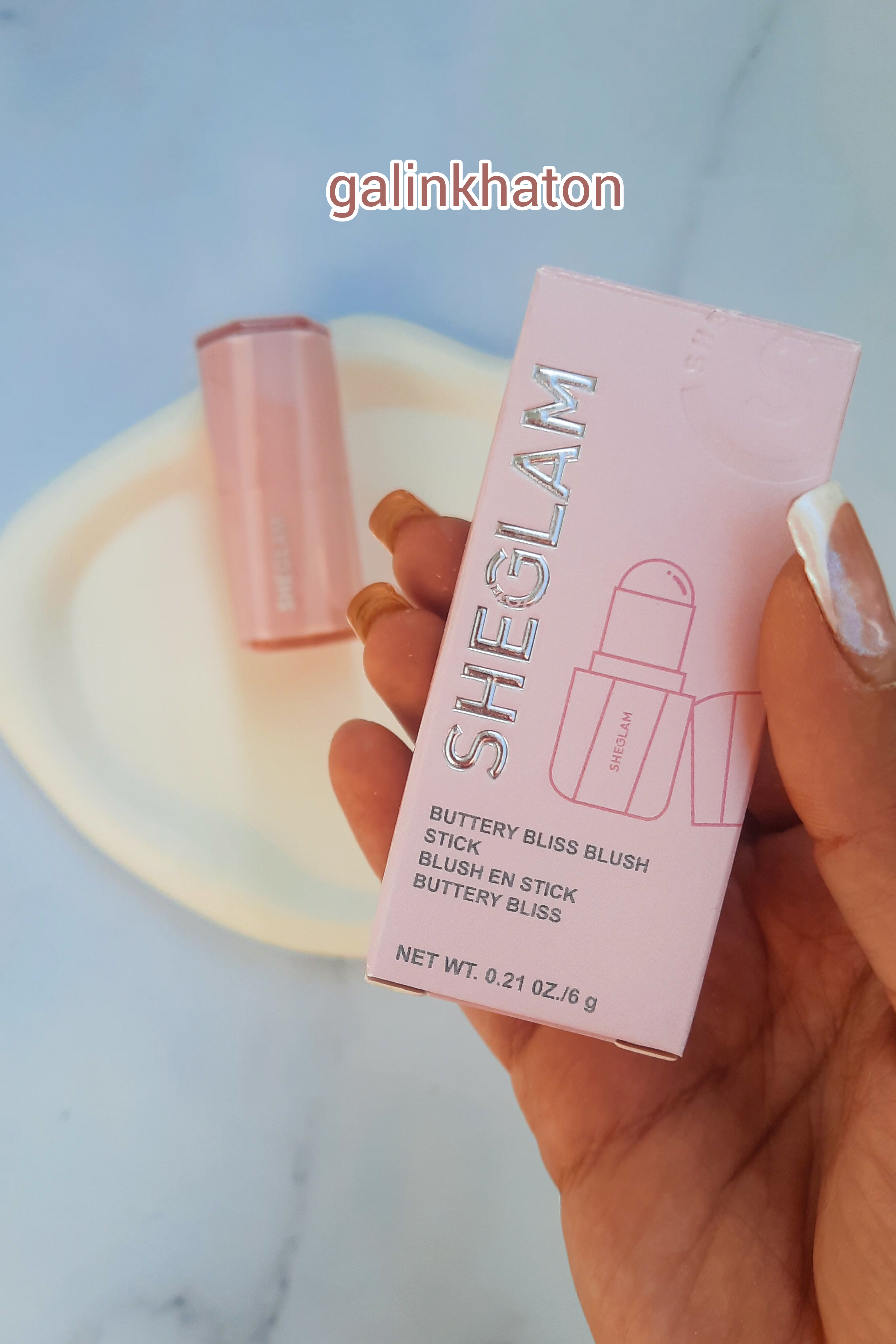 رژگونه Sheglam روی سنگ سفید با جعبه در دست، نمایش نمای نزدیک بسته‌بندی محصول