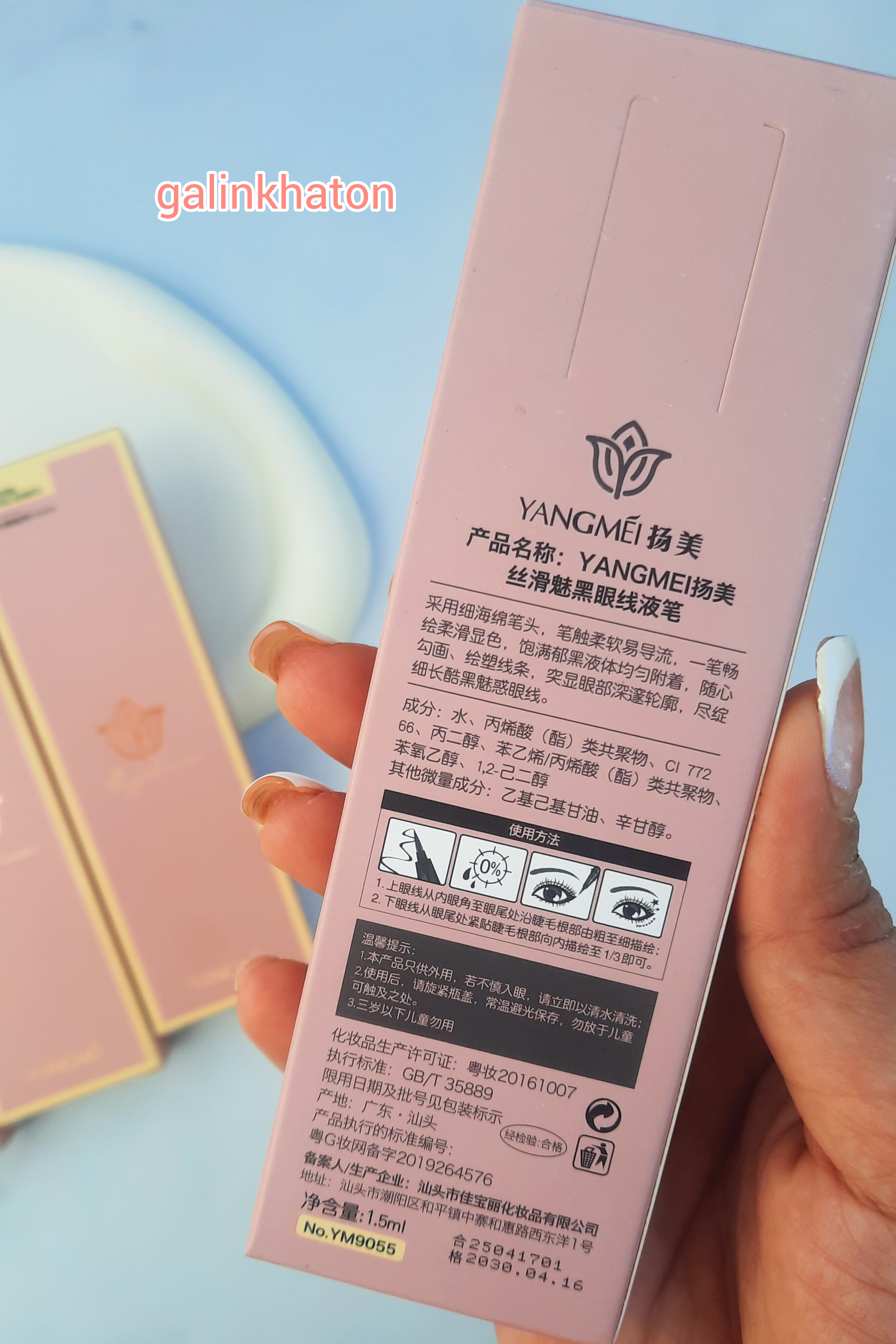 جعبه خط چشم یانگمی مشکی در دست، نمای نزدیک پشت جعبه و جزئیات محصول، انتخاب حرفه‌ای آرایش لب و چشم