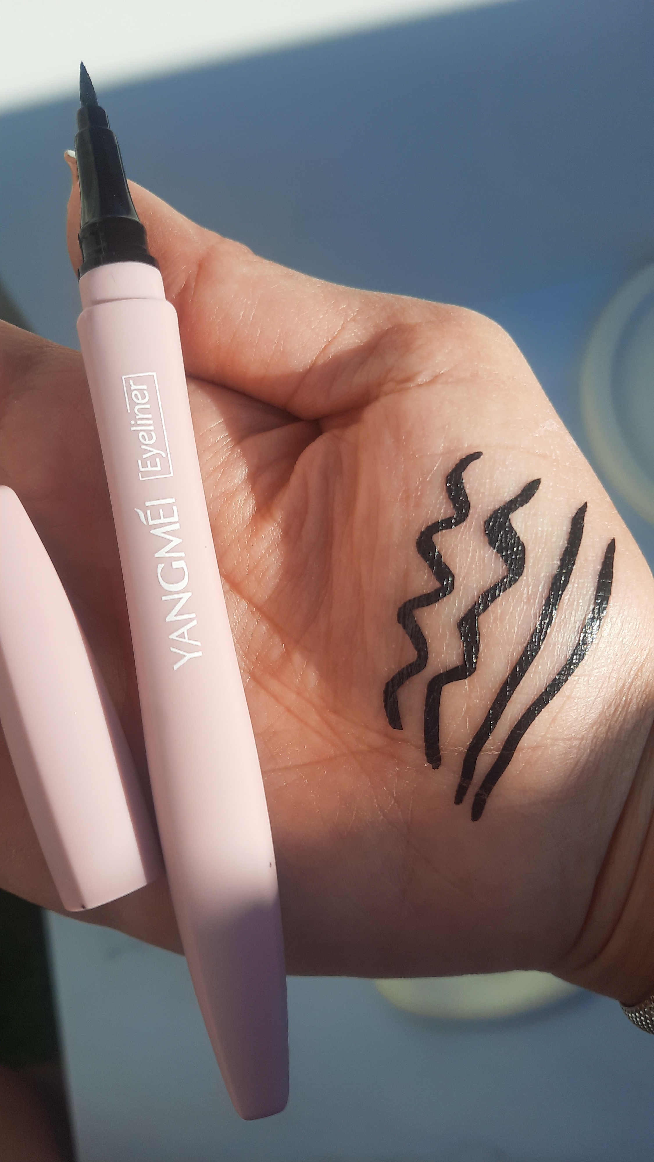 تست رنگ خط چشم یانگمی مشکی روی دست، نور طبیعی، نمای دقیق رنگ و بافت، آرایش حرفه‌ای و دقیق